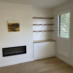 Fitted oak shelving and combination oak and white cupboard around fireplace